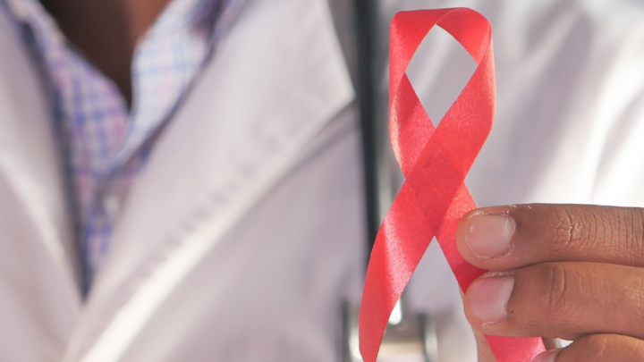 Stock image of someone holding the HIV red ribbon